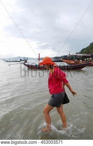 Traveler Thai Women Playing Water In Sea Ocean On Eastern Shore Of The Gulf Of Thailand While Rainin