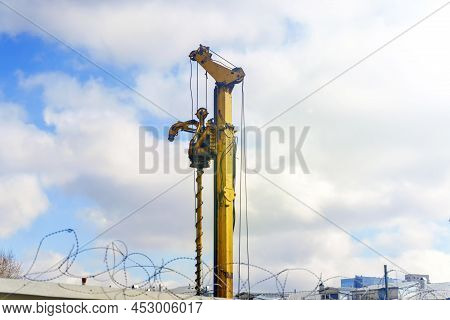 Drilling Rig Of Yellow Color Against The Background Of The Sky With Clouds.