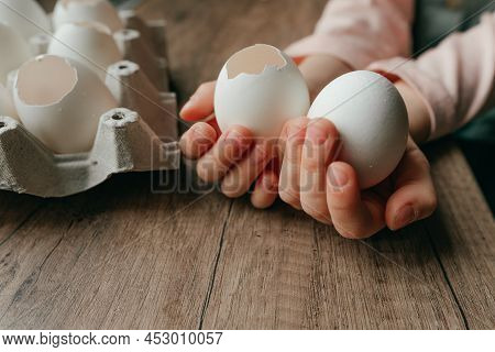 Little Girl Holding An Egg And An Empty Eggshell In Her Hands