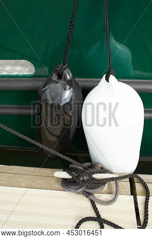 Black And White Fenders Suspended Between A Boat And Dockside For Protection. Maritime Fenders