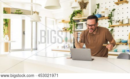 Cheerful Young Man Thrilled For Making Last Minute Reservation For Vacation Standing In His Kitchen 