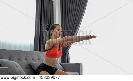 Young Muscular Fitness Woman Doing Half Squats Exercise At Home On Living Room ,sofa Workout