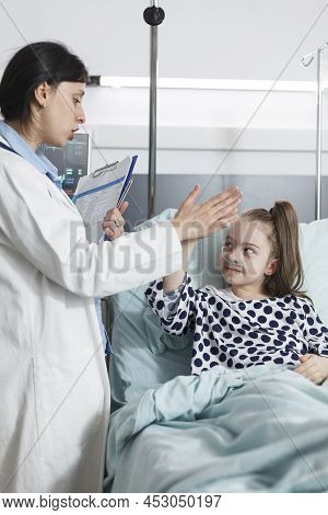 Happy Cheerful Young Patient Highfive Pediatric Expert While In Medical Examination Room. Healthcare