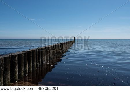 Maritime Background, Wooden Breakwater In Calm Baltic Sea Against Blue Sky