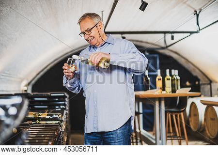 Portrait Of Senior Man Who Owns Winery. He Is Examining Quality In His Wine Cellar. Industry Wine Ma