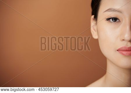 Half Face Of Young Asian Woman With Eye Liner And Lip Tint Looking At Camera