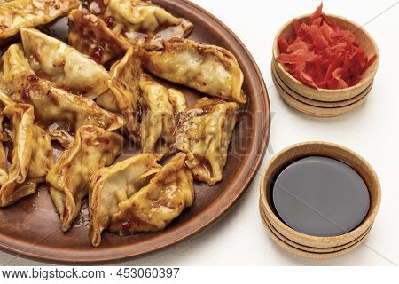 Boiled Gedza Dumplings In Sauce On Ceramic Plate. Pickled Ginger And Soy Sauce In Bowls. Top View. W
