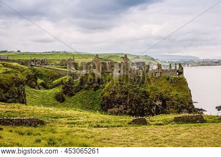 Ruins Of Dunluce Castle, Antrim, Northern Ireland During Sunny Day With Semi Cloudy Sky. Irish Ancie