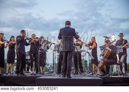 Orchestra Playing Classic Instrumental Music Under Cloudy Sky