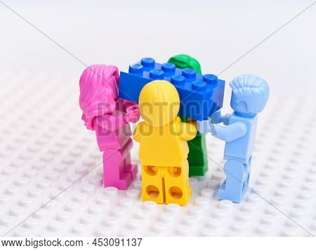 Tambov, Russian Federation - October 17, 2021 Four Monochrome Lego Minifigures Carrying A Blue Lego 