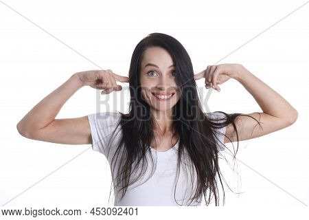 Portrait Of Smiling Woman Puts Fingers In Ears. Positive Emotions And Extraneous Noise Concept
