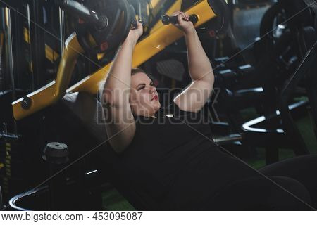 Overweigh woman working out on a fitness equipment in sport club