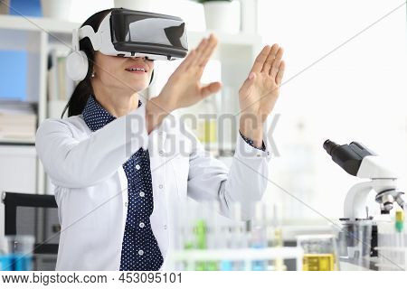 Young Female Doctor In Virtual Reality Headset Works On Computer In Hospital Office. Offi Vr Headset