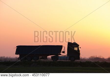 Semi-truck With Tipping Cargo Trailer Transporting Sand From Quarry Driving On Highway Hauling Goods