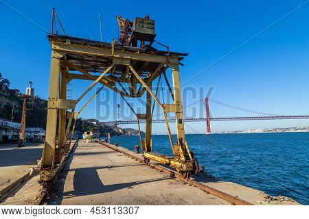 Almada; Portugal - March 01; 2022: Old deep water terminal, derived products and oleaginous products in Almada, Portugal with fishing boats near the beach