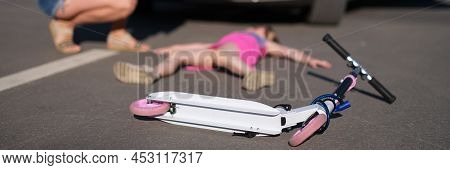 Little Girl Lies Motionless On Asphalt With Scooter After Collision With Car.