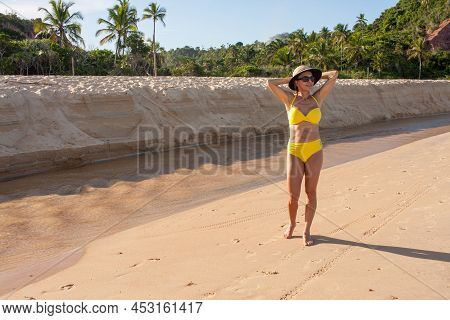 Fit Women In A Yellow Bikini At The Beach Known As Pitinga, In Arraial D\' Ajuda, Bahia, Brazil