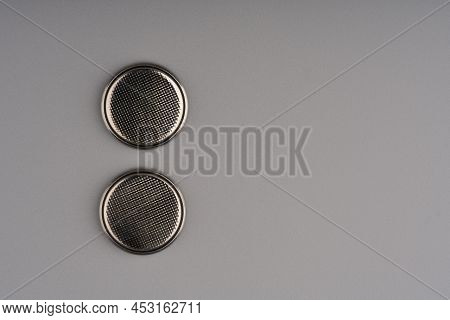 Two Round Flat Batteries Commonly Used For Tv Remote Controls On A Gray Background. Lots Of Space Fo
