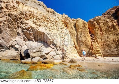 Cute teen girl enjoying secluded Tsigrado beach surrounded by amazing cliffs on Greek island of Milos
