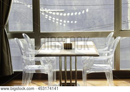 Wooden Dining Table And Plastic Chairs And Industrial Lamp At Hotel And Light From Window, Empty Tab