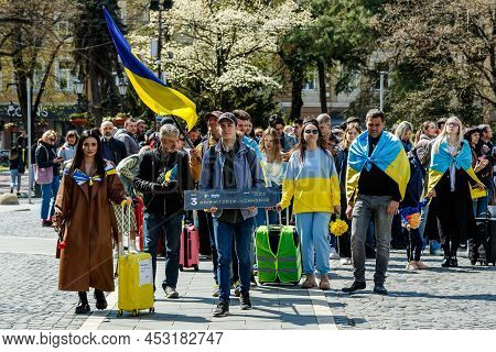 Uzhhorod, Ukraine - April 19, 2022: Ukrainian Refugees With Suitcases Walk In The City Center During