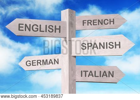 Wooden Signpost With Names Of Different Languages Against Blue Sky