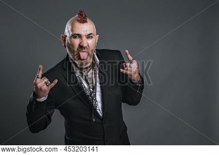 Punky-style Man Dressed In Suit Jacket Sticks Out His Tongue And Makes Horn Signal With His Hands Lo