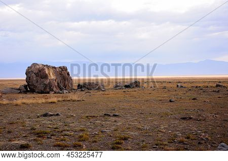 Remains Of An Ancient Stone Sanctuary In The Dried Autumn Steppe Under A Cloudy Sky.