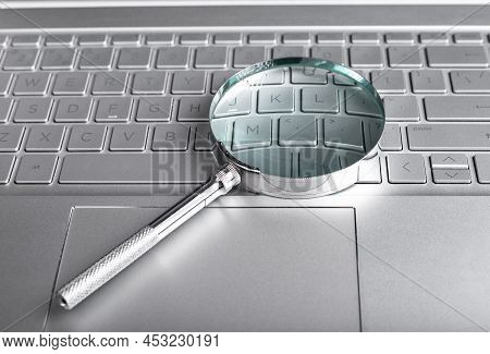 Magnifying Glass On Laptop Keyboard. Information Search Concept. Digital Databases Study. Audit Cond