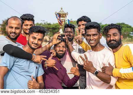 Group Of Cricker Players Celebrating Victory Of Cricket Match By Holding Trophy And By Lifting Capta