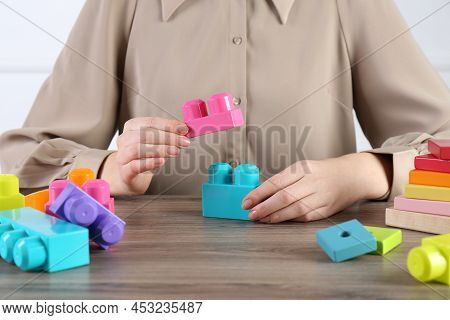 Aba Therapist With Colorful Building Blocks At Wooden Table, Closeup