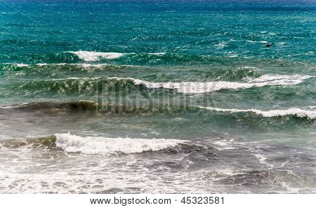 Mare agitato con onde spumeggianti e sfumature di blu e verdi.