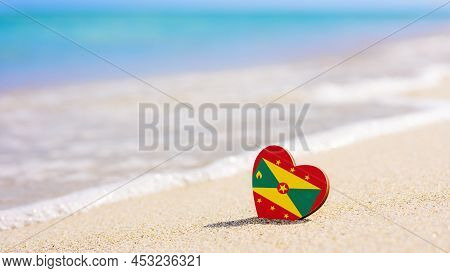 Flag Of Grenada In The Shape Of A Heart On A Sandy Beach. The Concept Of The Best Vacation In Grenad