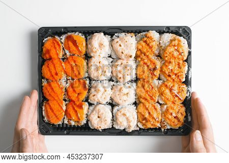 Close-up Of Courier's Hands Holding Set Of Hot Baked Yaki Maki Rolls In Plastic Box, Top View. Deliv