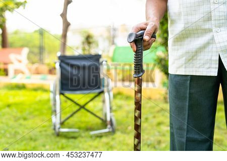 Old Man Waliking By Using Stick In Front Of Wheelchair At Hospital Garden - Concept Of Healthcare, R