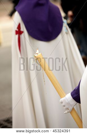 Nazareno sosteniendo la vela durante un desfile de semana Santa.