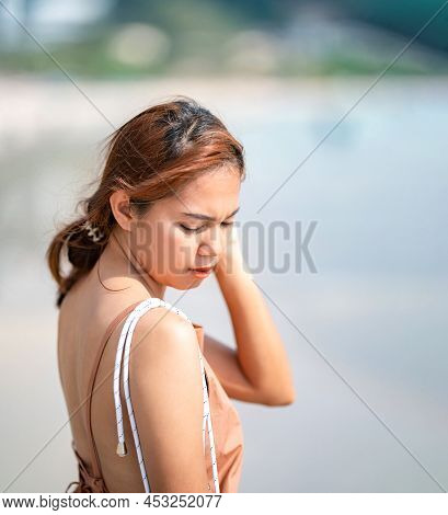Beautiful Relaxed Thai Woman Poses On The Beach In The Sunlight  With Happiness And Relaxation.