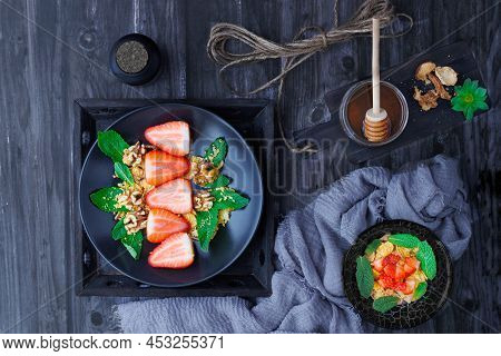 Dark Table With Plates With Strawberries, Mint And Nuts Overhead View
