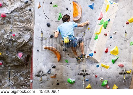 The Climber Trains On The Artificial Rock Wall With Insurance In Bouldering Gym, April 2022, Prague,