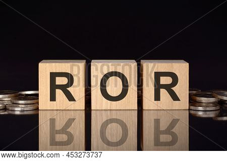 Ror - Text On Wood Blocks On Black Background With Coins. Front View. Business Concept