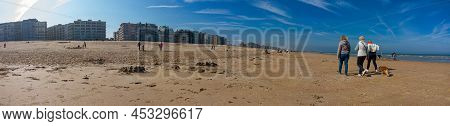 Panoramic View On Sand Beach With People Walking Or Playing On The Beach On A Sunny Springday