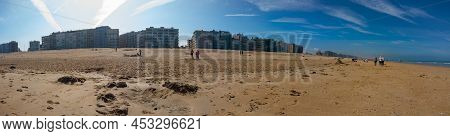 Panoramic View On Sand Beach With People Walking Or Playing On The Beach On A Sunny Springday