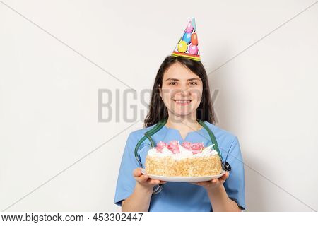 A Woman In A Festive Cap Holds A Cake, A Place For Text, With The Day Of The Doctor Or Nurse.