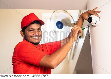 Happy Smiling Electrician Looking At Camera While Fixing Cctv Surveillance Camera At Home - Concept 