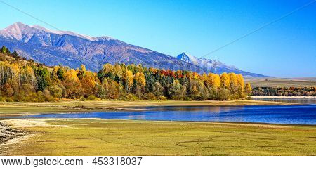 Lake, Mountains And Colofrful Trees In Forest. High Tatras With Peak Krivan At Background