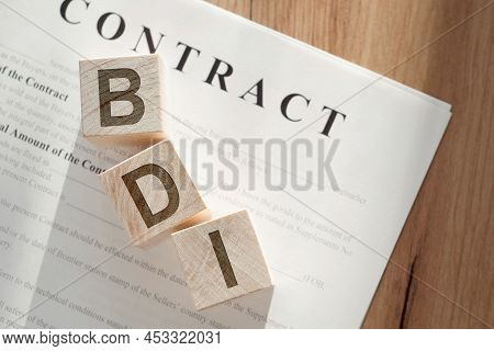 Wooden Cubes With The Word Bdi - Brand Development Index On A Paper Contract.