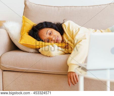 Happy And Smiling African-american Woman Lying Down On Couch And Watching Movies On Laptop