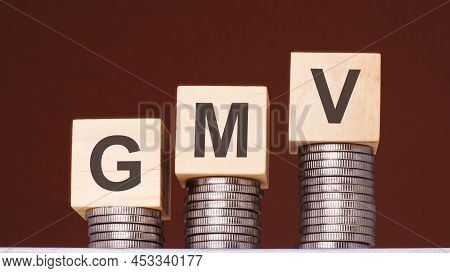 Text Gmv Written On Wooden Blocks With Stacked Coins On Brown Background. Business Concept, Gmv - Sh