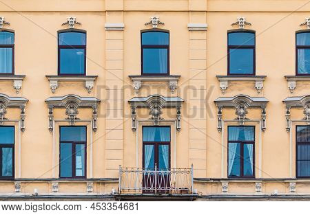 Balcony And Many Windows In A Row On The Facade Of The Urban Historic Apartment Building Front View,