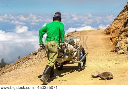Miner Extracting Sulfur Inside The Crater Of Active Volcano Ijen, Java Island, Indonesia